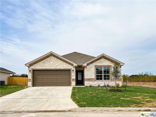 view of front of home featuring a garage, central air condition unit, and a front lawn