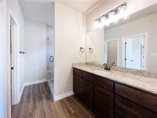 bathroom with hardwood / wood-style flooring, vanity, and walk in shower