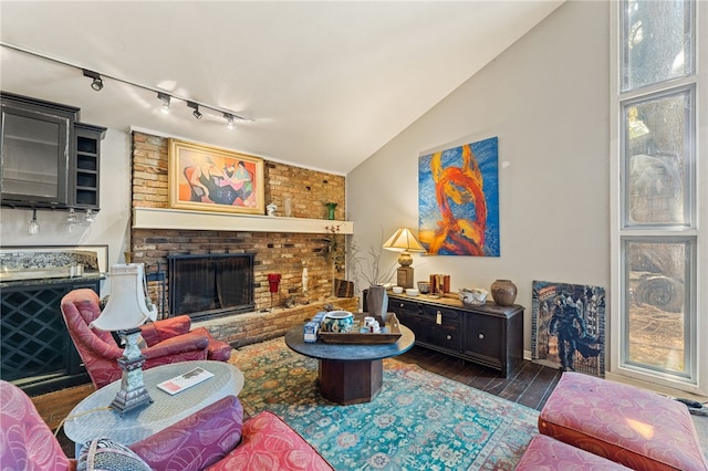 living room with rail lighting, dark hardwood / wood-style flooring, a fireplace, and vaulted ceiling