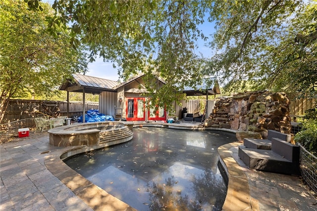 view of pool featuring a jacuzzi, french doors, and a patio