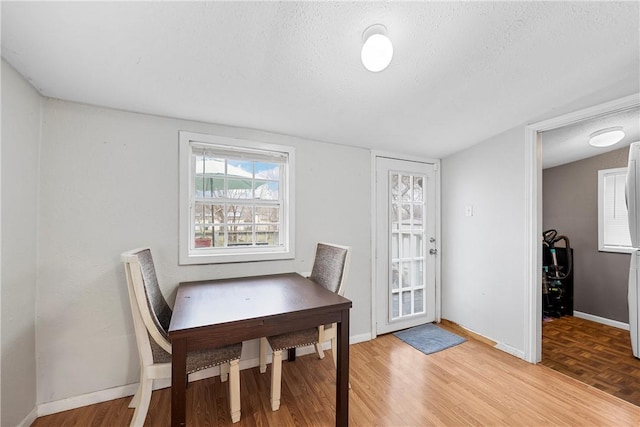 dining room featuring light wood-type flooring and a textured ceiling