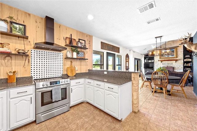 kitchen with a textured ceiling, stainless steel range oven, white cabinetry, and wall chimney range hood