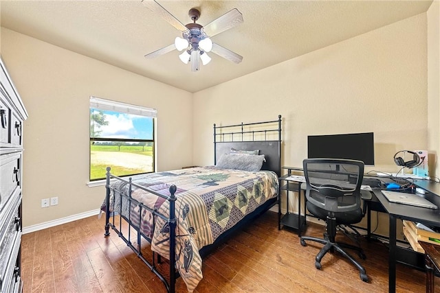 bedroom with hardwood / wood-style floors, ceiling fan, and a textured ceiling