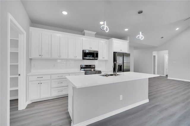 kitchen featuring appliances with stainless steel finishes, sink, a center island with sink, white cabinetry, and hanging light fixtures