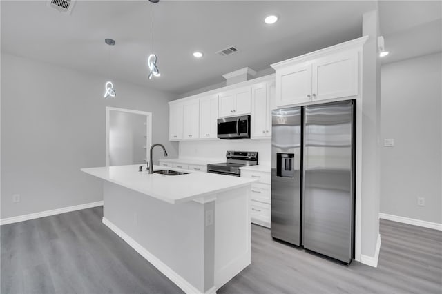 kitchen with appliances with stainless steel finishes, sink, decorative light fixtures, white cabinetry, and an island with sink