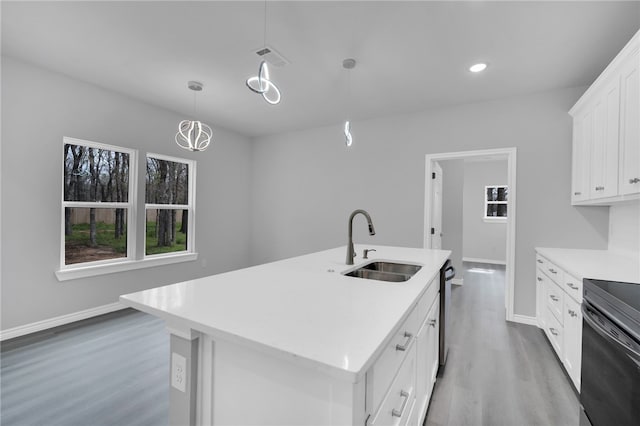 kitchen with white cabinetry, sink, hanging light fixtures, wood-type flooring, and a kitchen island with sink