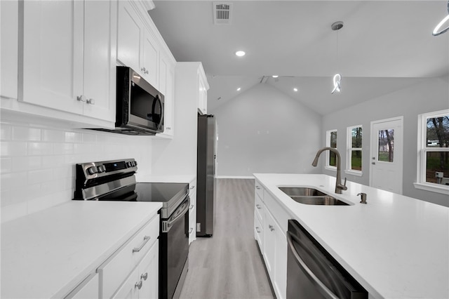 kitchen featuring pendant lighting, sink, vaulted ceiling, appliances with stainless steel finishes, and white cabinetry