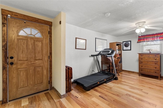 workout area featuring a textured ceiling, light hardwood / wood-style floors, and ceiling fan