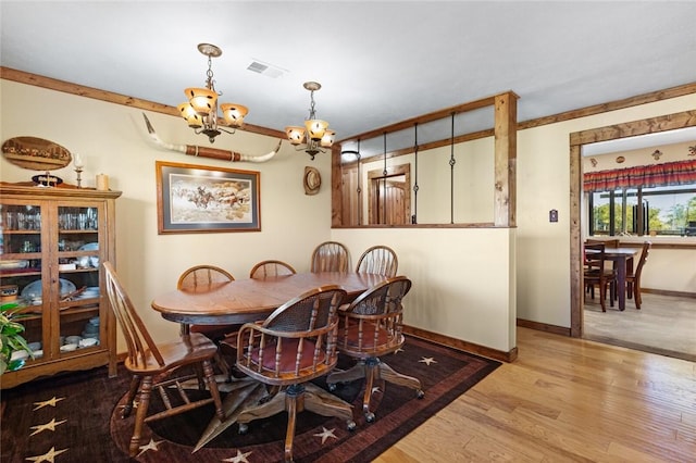 dining area with wood-type flooring, ornamental molding, and a notable chandelier