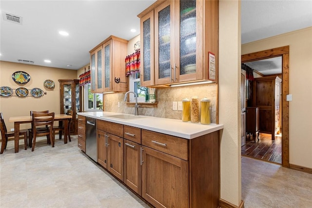 kitchen featuring stainless steel dishwasher, sink, and backsplash