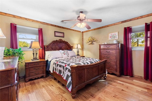 bedroom with ceiling fan, ornamental molding, and light hardwood / wood-style flooring