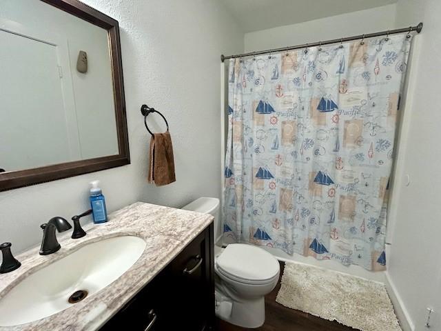 full bathroom with vanity, wood-type flooring, toilet, and shower / tub combo with curtain