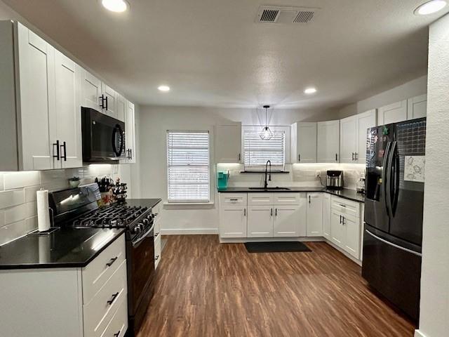 kitchen with sink, white cabinets, and black appliances