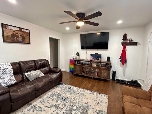 living room featuring dark wood-type flooring and ceiling fan