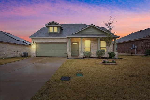 view of front of property featuring driveway, stone siding, an attached garage, a front lawn, and central AC