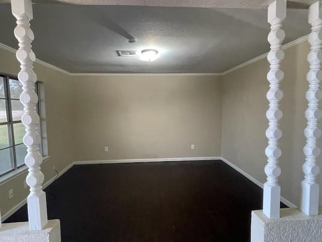 spare room with a textured ceiling, ornamental molding, visible vents, and baseboards