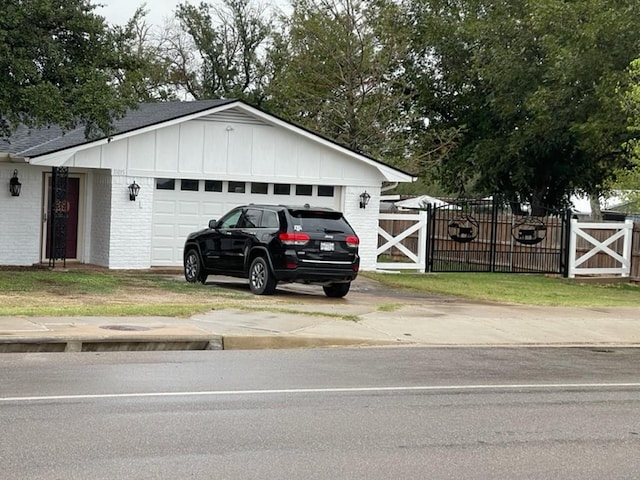 exterior space featuring board and batten siding, a gate, brick siding, and a garage