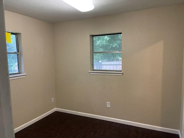 spare room featuring dark wood-style floors and baseboards