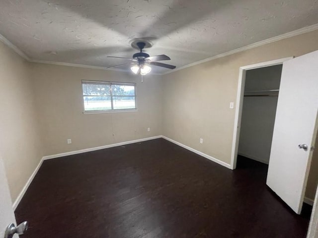 unfurnished bedroom featuring ornamental molding, ceiling fan, dark wood-type flooring, and baseboards