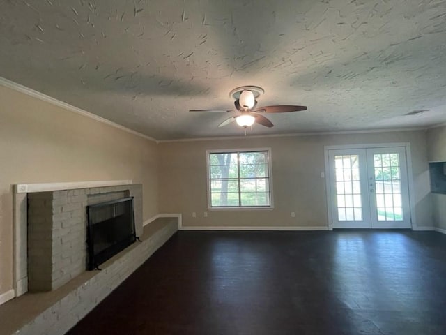 unfurnished living room with a textured ceiling, a fireplace, wood finished floors, baseboards, and ornamental molding