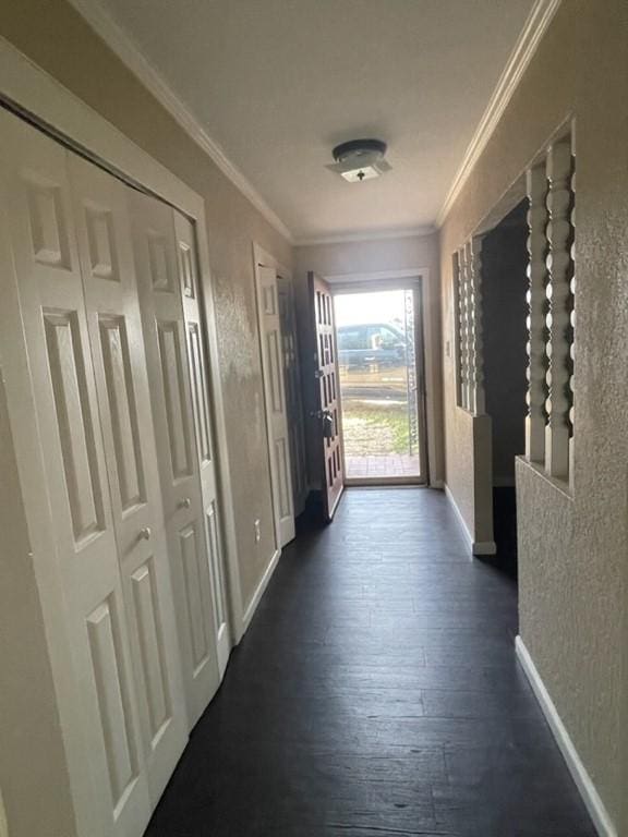 corridor with ornamental molding, dark wood-style flooring, a textured wall, and baseboards