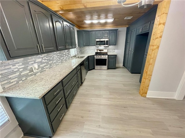 kitchen featuring sink, backsplash, stainless steel appliances, light stone counters, and light hardwood / wood-style floors