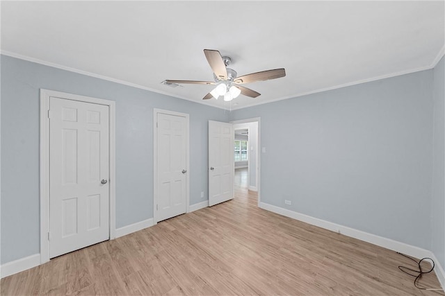 unfurnished bedroom with ceiling fan, light hardwood / wood-style floors, ornamental molding, and two closets