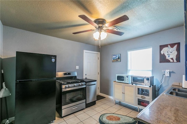 kitchen with sink, a textured ceiling, light tile patterned floors, appliances with stainless steel finishes, and ceiling fan