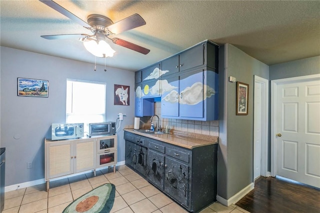 kitchen with blue cabinetry, light tile patterned flooring, sink, a textured ceiling, and backsplash