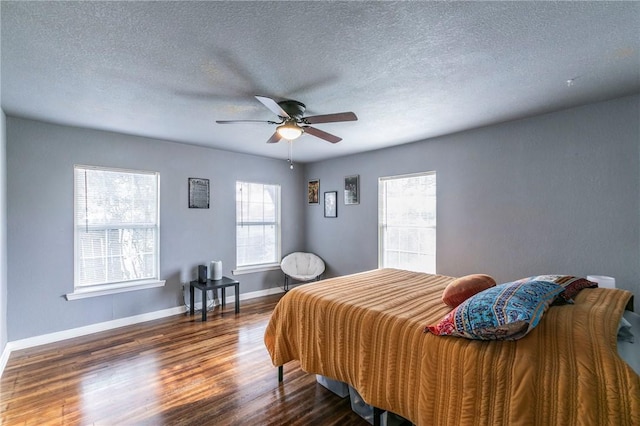 bedroom with dark wood-type flooring, a textured ceiling, and ceiling fan