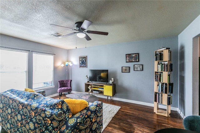 living room with dark wood-type flooring, a textured ceiling, and ceiling fan