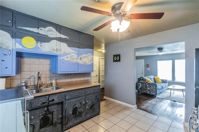 kitchen with backsplash, light tile patterned floors, blue cabinetry, and sink