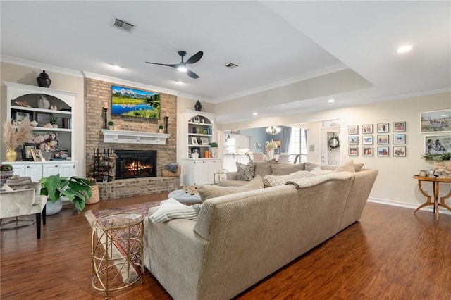 living room with dark wood finished floors, visible vents, a fireplace, and ornamental molding