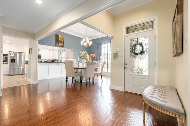 entrance foyer featuring an inviting chandelier, crown molding, wood finished floors, and baseboards