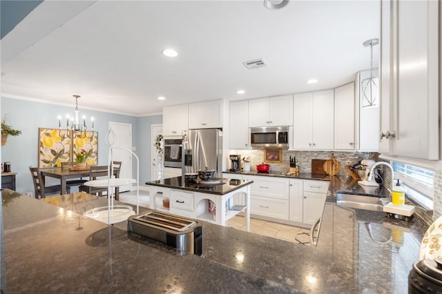 kitchen featuring ornamental molding, decorative backsplash, a sink, white cabinets, and stainless steel appliances