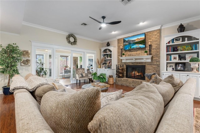 living room with a brick fireplace, wood finished floors, and ornamental molding