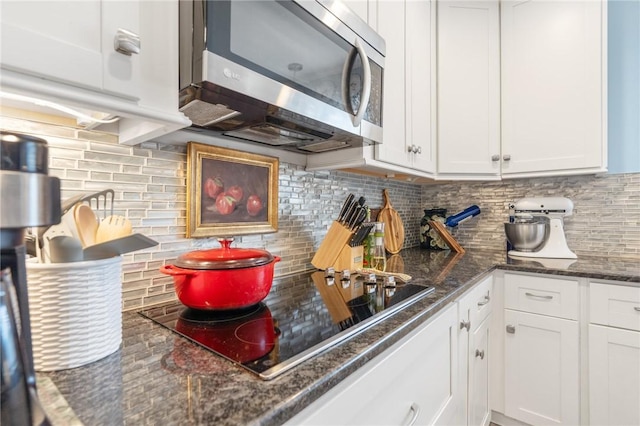 kitchen with stainless steel microwave, white cabinetry, black electric cooktop, and decorative backsplash