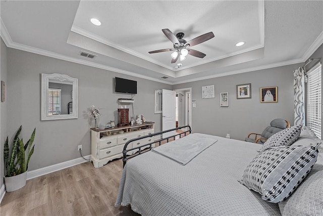 bedroom with ceiling fan, light hardwood / wood-style floors, crown molding, and a raised ceiling