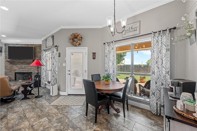 dining space featuring a notable chandelier, a stone fireplace, and crown molding