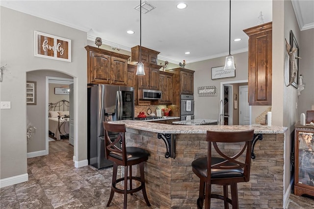 kitchen featuring a kitchen breakfast bar, decorative light fixtures, light stone countertops, ornamental molding, and stainless steel appliances