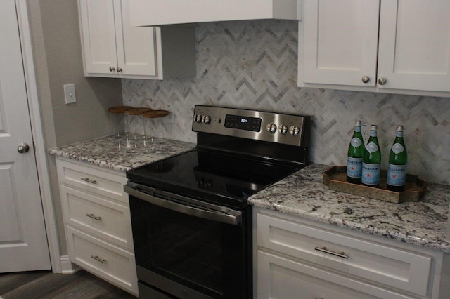 kitchen featuring stainless steel electric range oven, white cabinets, light stone counters, and dark hardwood / wood-style floors