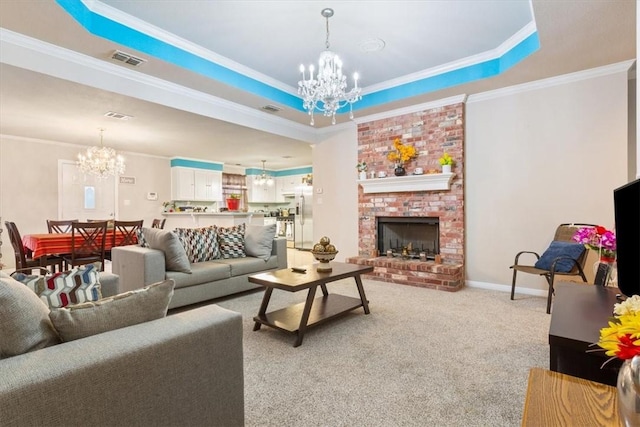 carpeted living room with crown molding, a fireplace, a raised ceiling, and a chandelier