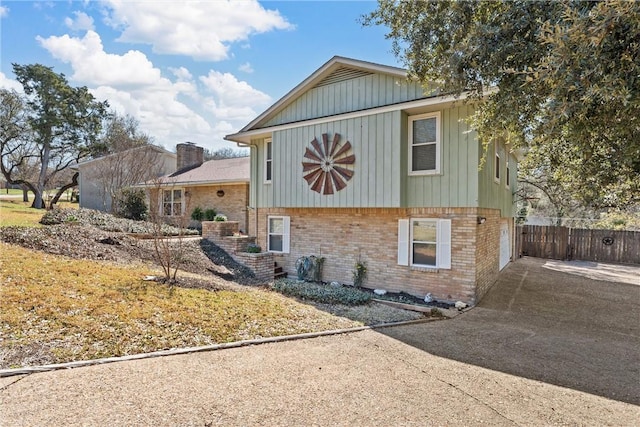 exterior space with concrete driveway, fence, and brick siding