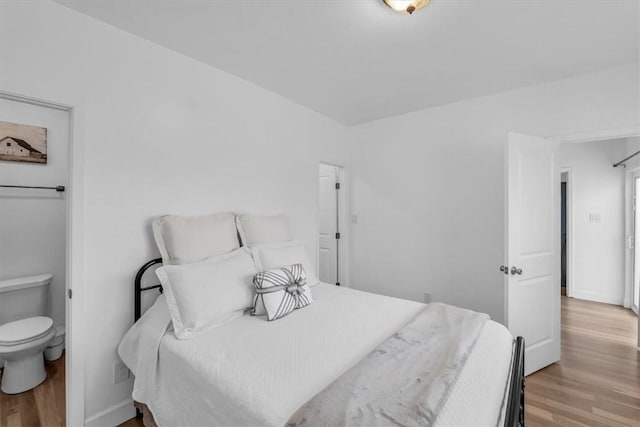 bedroom featuring connected bathroom and light hardwood / wood-style floors