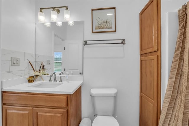 bathroom with vanity, toilet, and tasteful backsplash