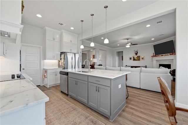 kitchen featuring appliances with stainless steel finishes, a kitchen island with sink, ceiling fan, sink, and pendant lighting