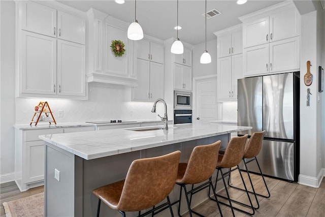 kitchen with a kitchen island with sink, white cabinets, and stainless steel appliances