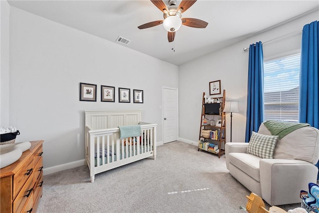 bedroom with ceiling fan, light colored carpet, and a crib