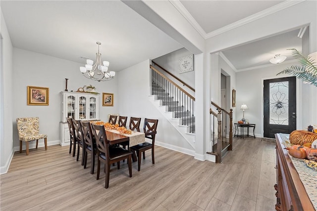 dining area with an inviting chandelier, light hardwood / wood-style flooring, and ornamental molding