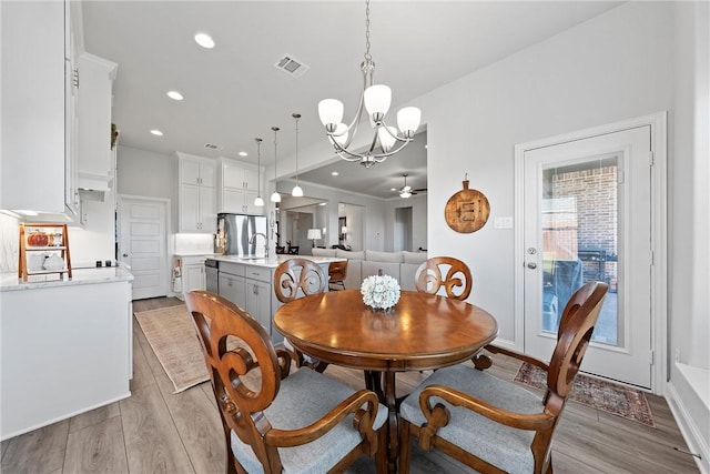 dining room with light hardwood / wood-style flooring, ceiling fan with notable chandelier, and sink